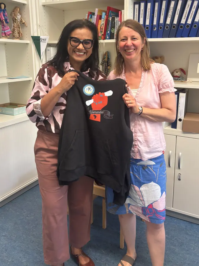 Als Gastgeschenk überreicht Sarojini Nadar einen Hoodie zur Campagne „Womandla“ des Desmond Tutu Centre // As a gift, Sarojini Nadar presents a hoodie from the “Womandla” campaign by Desmond Tutu Centre.