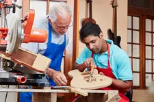 Bild Meister und Auszubildender arbeiten an einer Holzgitarre
