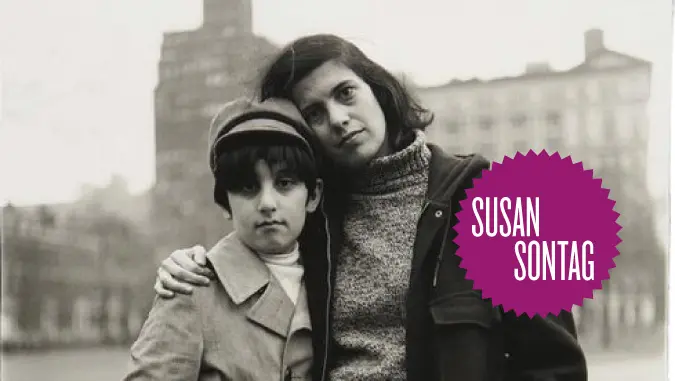 Die Autorin Susan Sontag vor städtischem Monument mit Mädchen im Arm