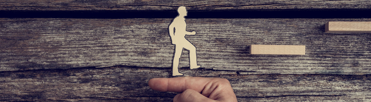 Businessman supporting paper cut out of a man climbing stairs