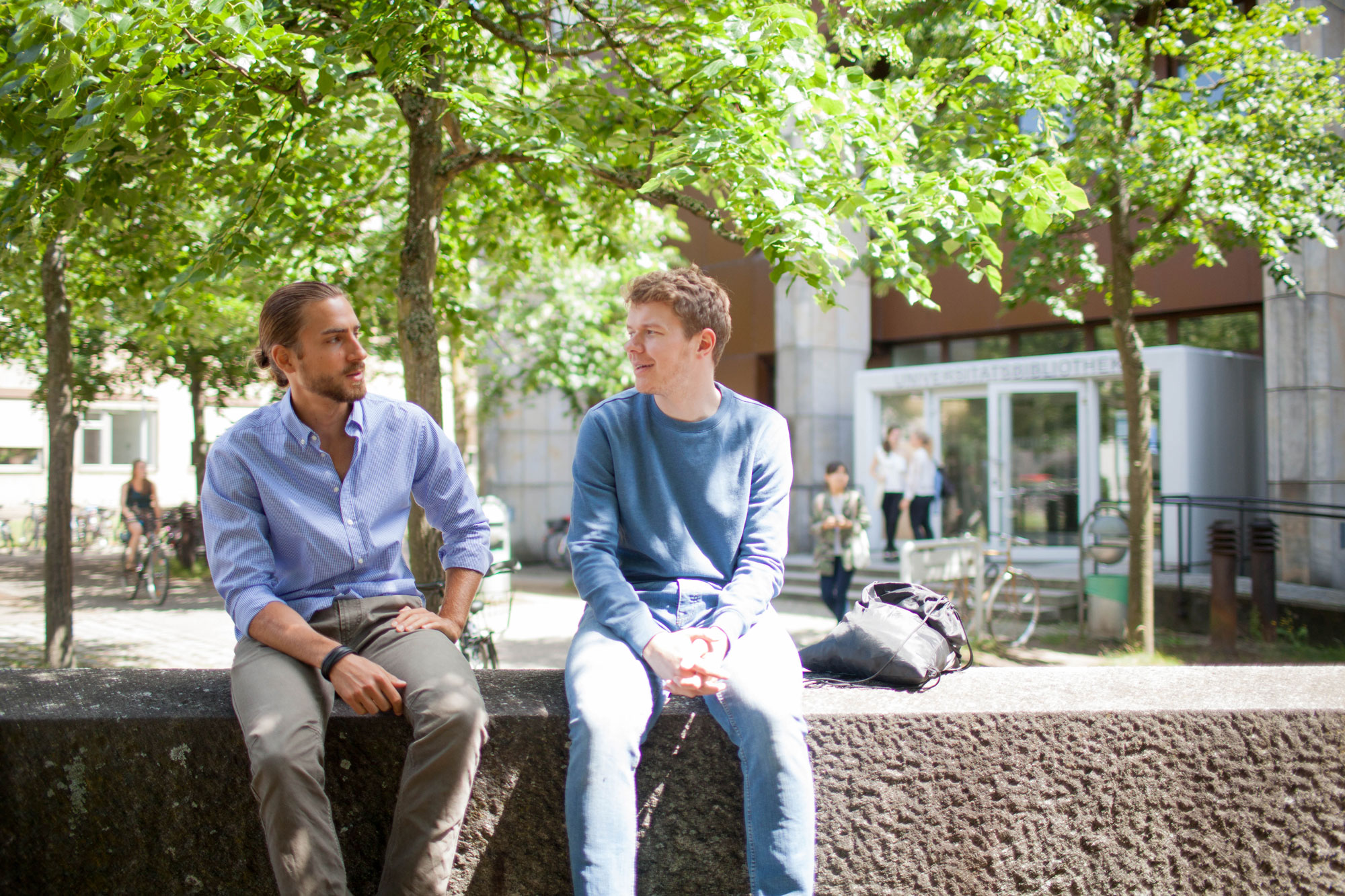 Studenten sitzen gemeinsam vor dem Feki-Gebäude