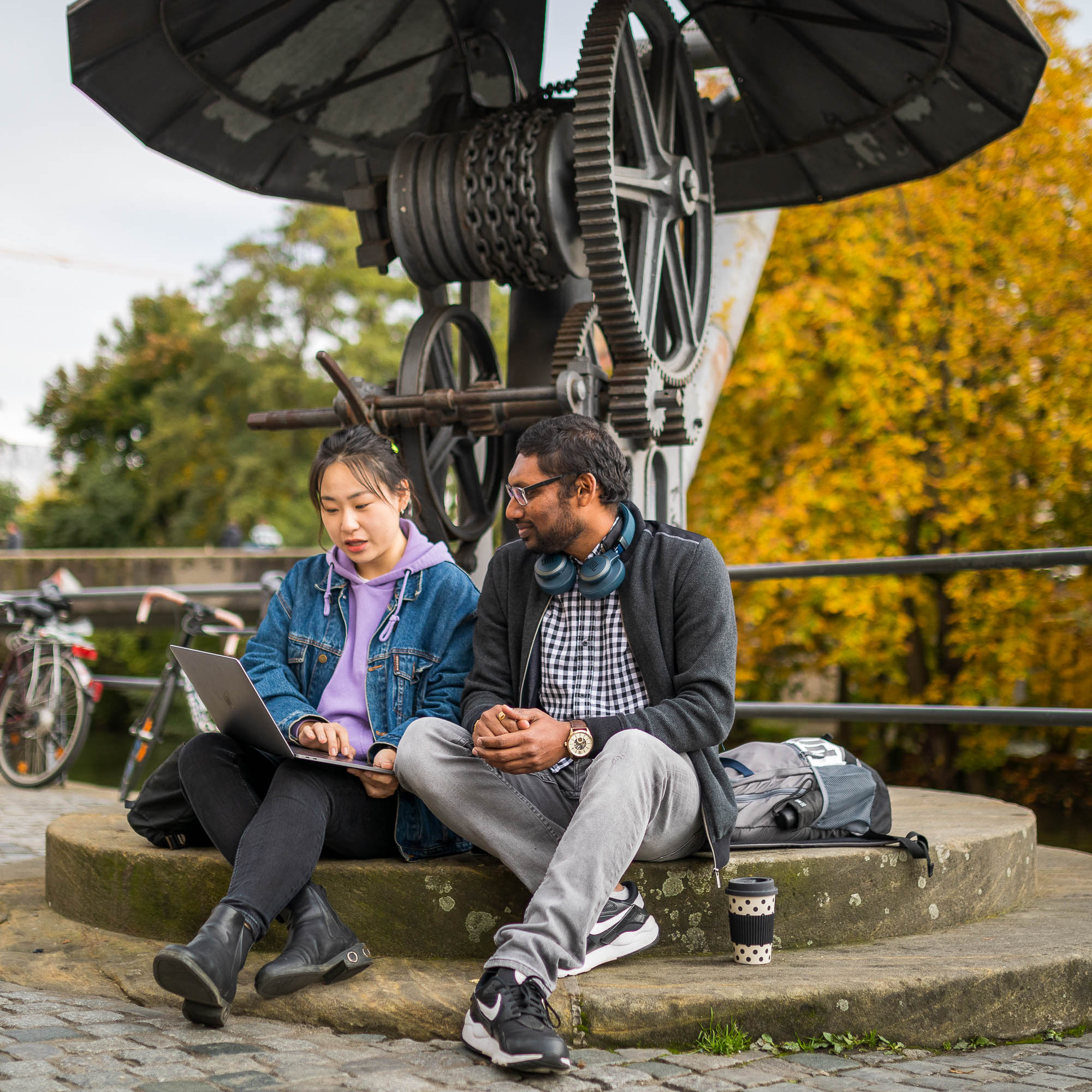 2 Studierende sitzen am Kranen und schauen gemeinsam in einen Laptop
