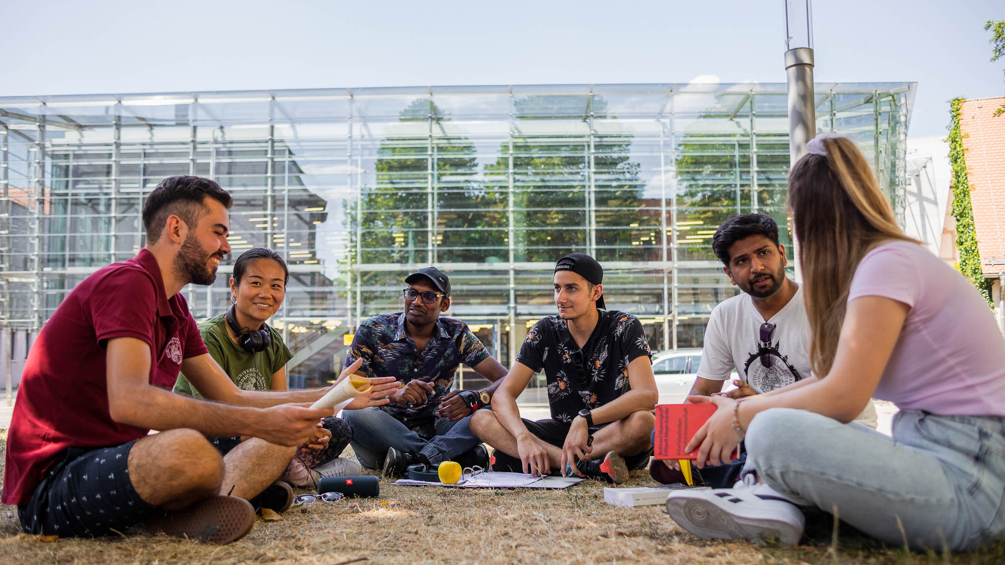 Studierende sitzen auf der Wiese vor der TB4 und lernen gemeinsam